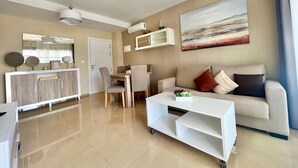 A modern living room with a sofa, coffee table, and dining area.