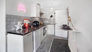 Una cocina moderna con armarios blancos, una encimera negra y un letrero de neón que dice 'let's party'.