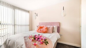 Un dormitorio con una cama, un arreglo floral grande y un banco con flores.