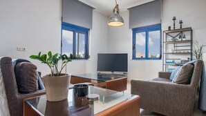 Una sala de estar moderna con una mesa de centro de vidrio, dos sofás, un televisor y una estantería.