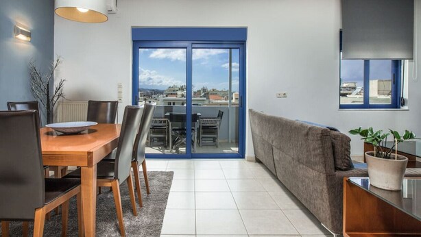 Una sala moderna con comedor, un sofá, una mesa de centro y vistas al exterior a través de un amplio ventanal corredero.