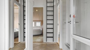 Un couloir menant à une chambre dotée d’une armoire intégrée, d’une échelle et donnant sur une salle de bain.
