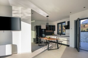 Een moderne keuken met een eethoek, een aan de muur bevestigde televisie en uitzicht op de omgeving.