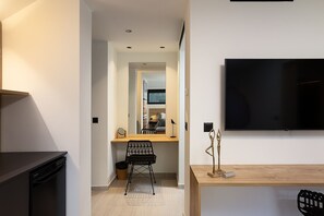 A modern kitchen with a dishwasher, a wooden dining table, and a TV mounted on the wall.