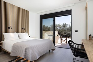 A modern bedroom with a bed, a wooden slat wall, a large sliding glass door leading to an outdoor area with a table and chairs.