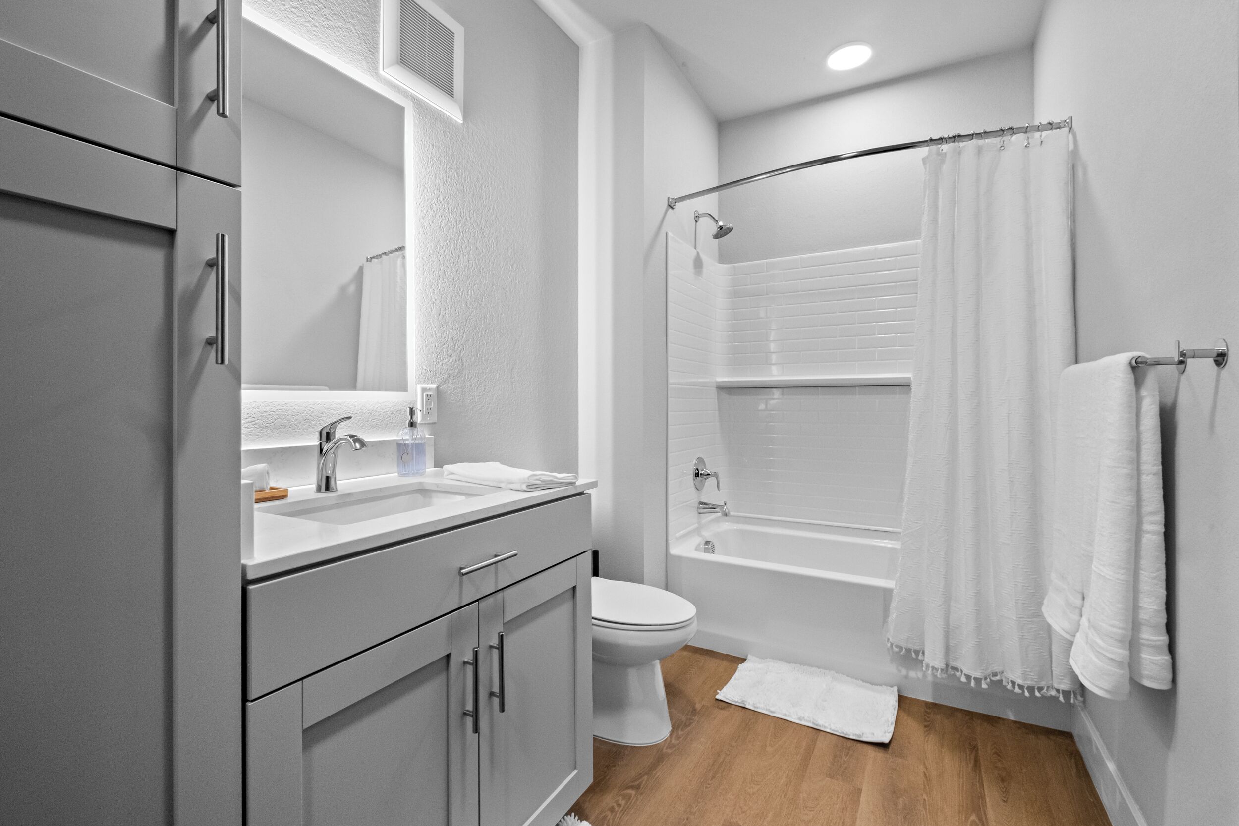 A modern bathroom with a white sink, toilet, and bathtub.