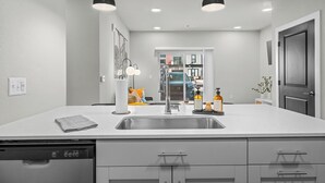 Una cocina moderna con una isla grande, pileta de acero inoxidable e iluminación colgante.