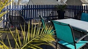 Un patio con mesa y sillas, una valla azul y casas al fondo.