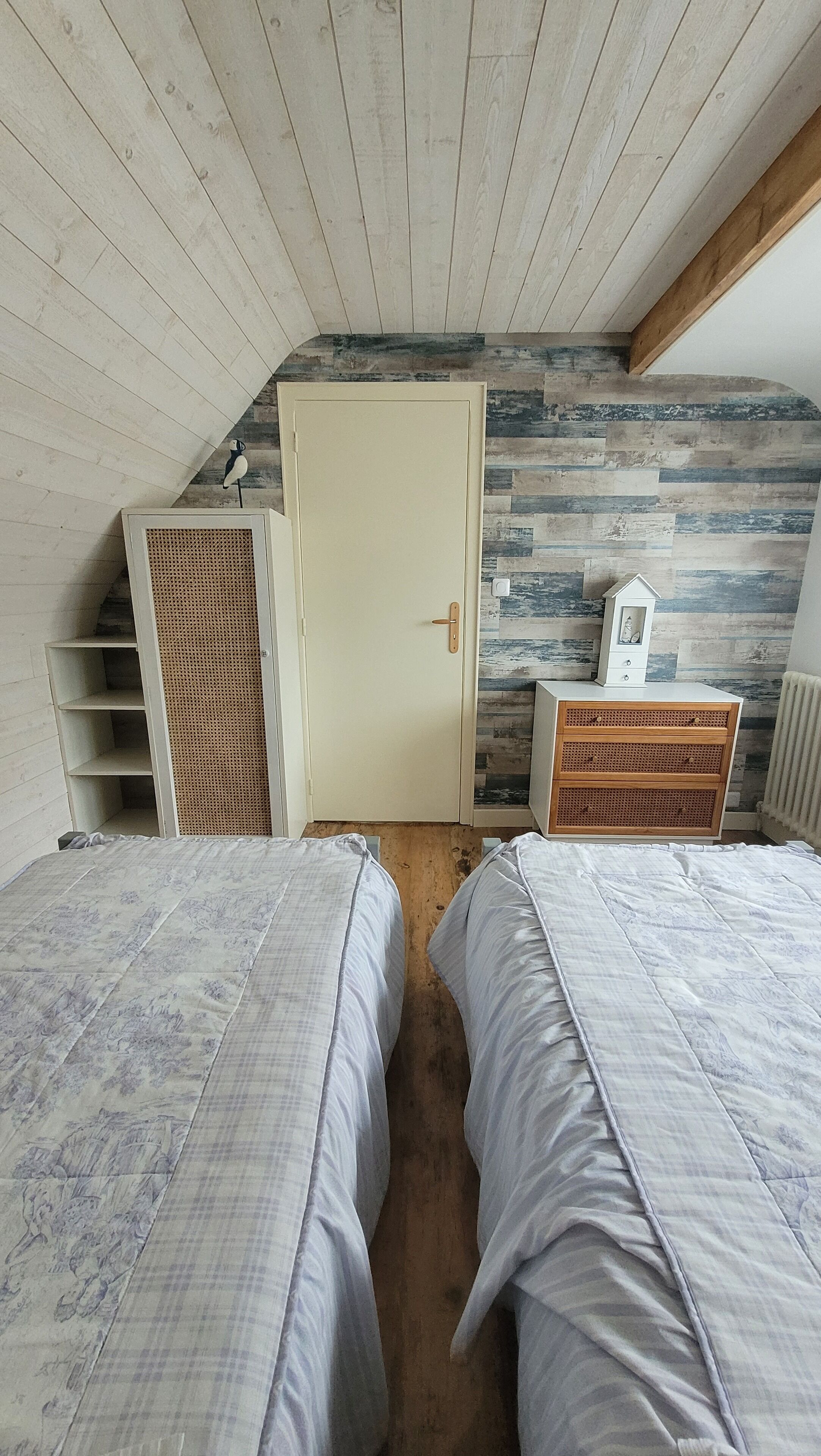 Una camera da letto con due letti, un armadio e un piccolo comò.