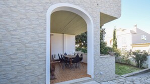 An outdoor dining area with a stone wall and a covered patio. - 3 bedroom cozy home in Lavinio (Lavinio)