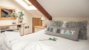 A bedroom with a skylight, a bed with a pillow labeled "RETEAT", a bedside table with a lamp, and a mirror on the wall. - Apartmentsleeps3-garden-hottub-parking (Padstow)
