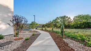 A pathway leading to a building with a white exterior, surrounded by landscaped areas with trees and shrubs. - Echo Suites Extended Stay Reno (Reno)