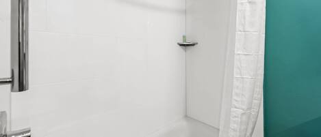 Ein Badezimmer mit weißen Fliesen, einem chromfarbenen Wasserhahn und einer Wand in Türkis.