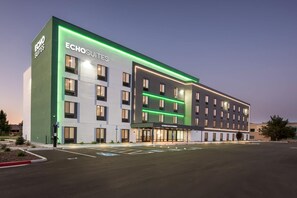 Moderni hotelli, jossa on selkeästi näkyvä ”ECHO SUITES” -kyltti, pysäköintialue ja hyvin valaistu julkisivu.
