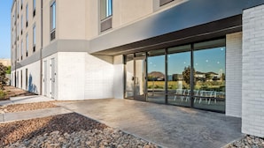 A modern building with a flat roof, large windows, and a paved courtyard with a gravel border. - Echo Suites Extended Stay Reno (Reno)