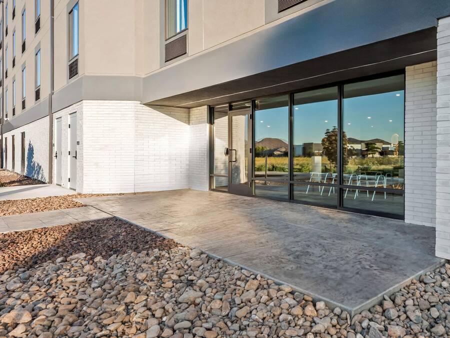 A modern building with a flat roof, large windows, and a paved courtyard with a gravel border.