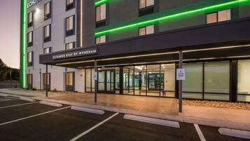 Un hotel con fachada moderna, luces de neón verdes y un letrero que indica estadías prolongadas de Wyndham.