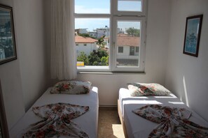 A room with two beds, a window with a view of buildings, and a framed picture on the wall. - Aydın Motel (Marmara)
