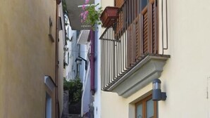 A narrow stone staircase leading to a building with a wooden door and a flower pot. - Le perle d'italia (Ravello)