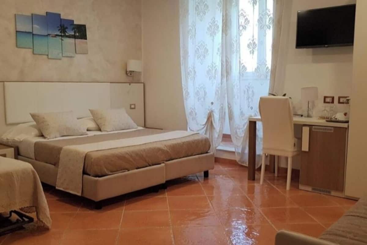 A hotel room with a bed, a desk, a chair, and a TV.