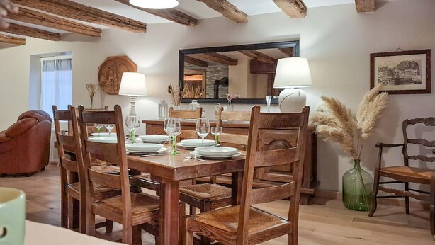 Zona pranzo con mobili in legno, uno specchio e un vaso con pannocchie di pampa.
