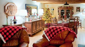 Un accogliente soggiorno con un mobile in legno, un albero di Natale e un'area pranzo apparecchiata per un pasto.