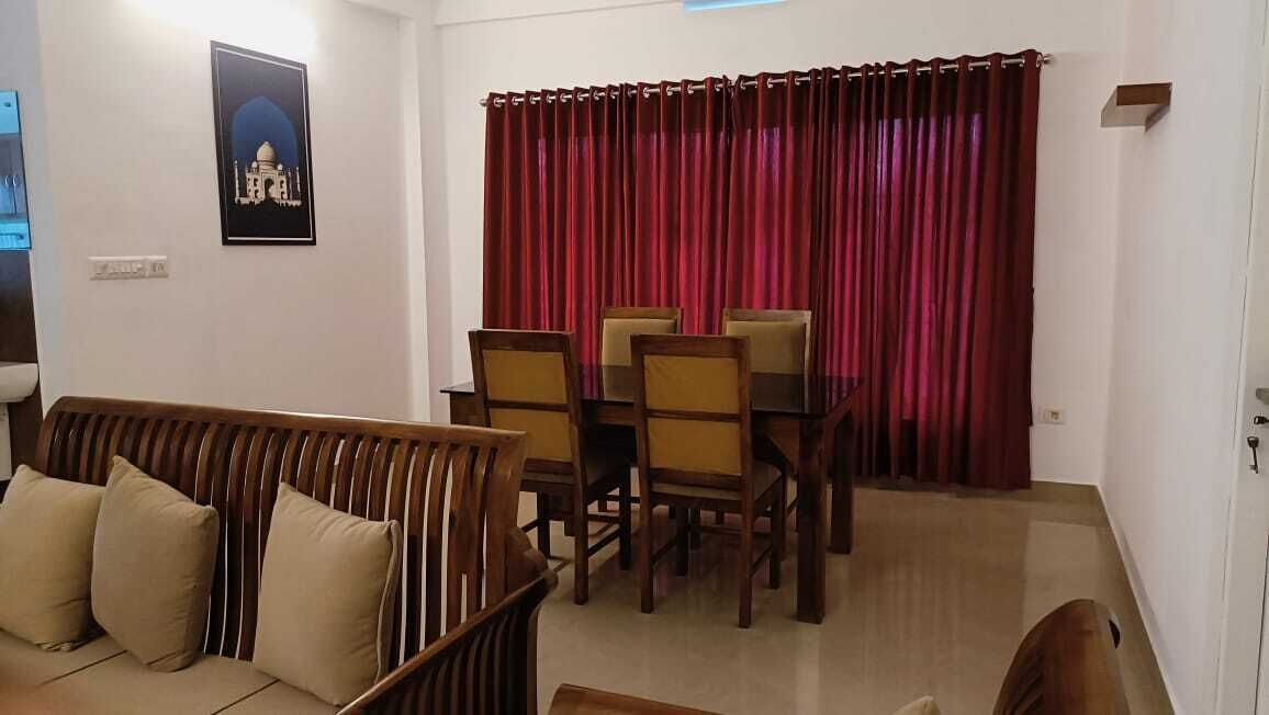 A dining area with a table and chairs, a sofa, and a red curtain.