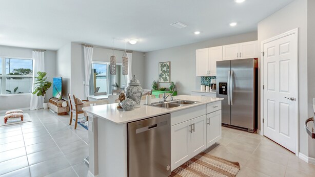 A modern kitchen with white cabinetry, a stainless steel refrigerator, and a dishwasher.
