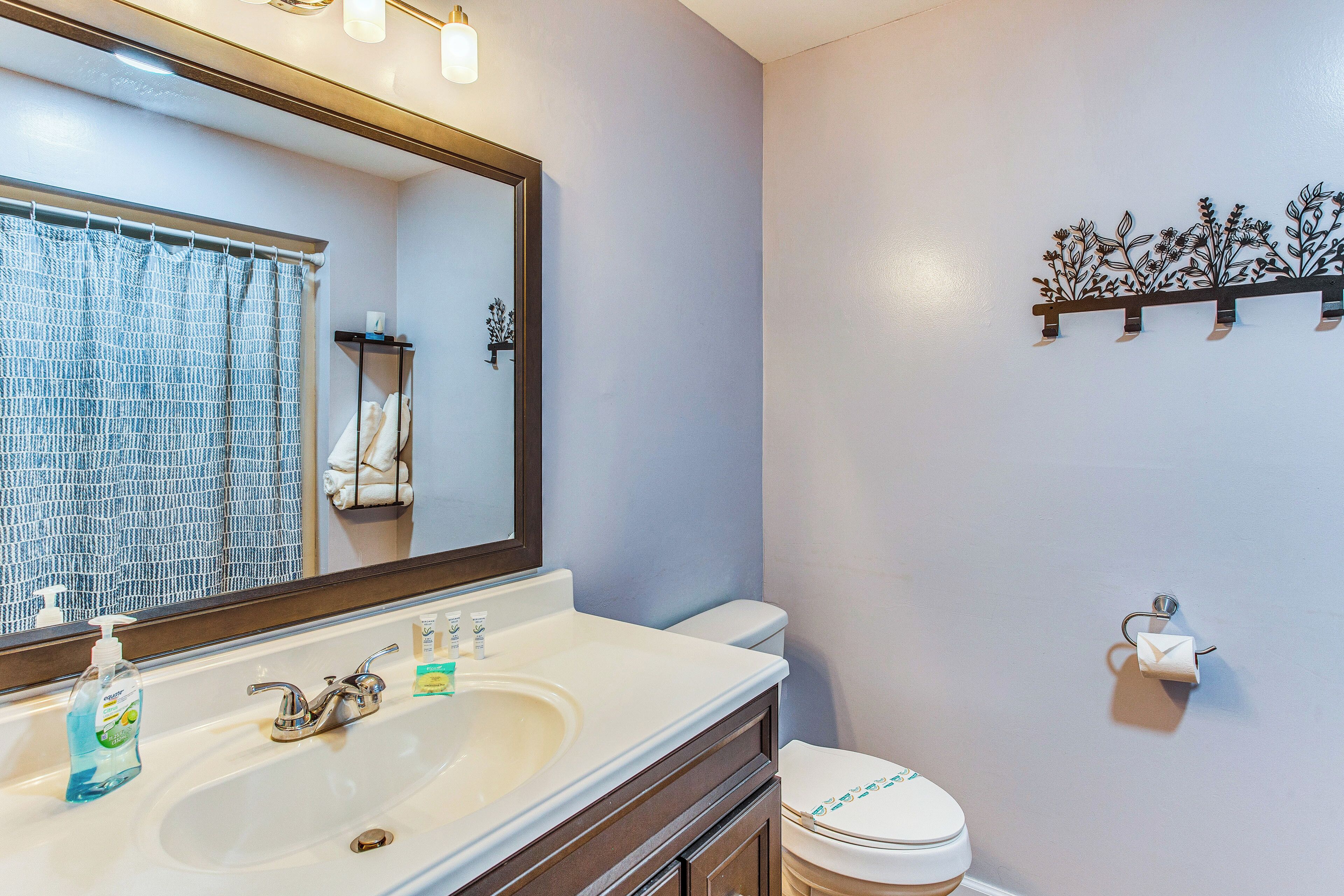A bathroom with a white sink, a mirror, a toilet, and a shower curtain.