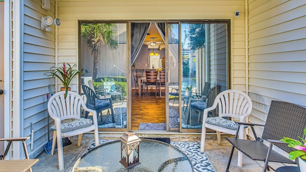 A covered patio with a glass door leading to an interior dining area, furnished with chairs and a table. - Walk to Ocean: Myrtle Beach Townhome w/ Patio (Myrtle Beach)