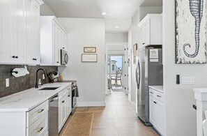 A modern kitchen with white cabinets, stainless steel appliances, and a view to the outside.