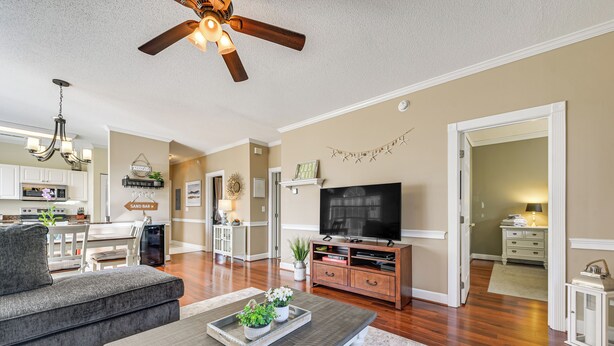 A living room with a sofa, coffee table, TV, and a ceiling fan.