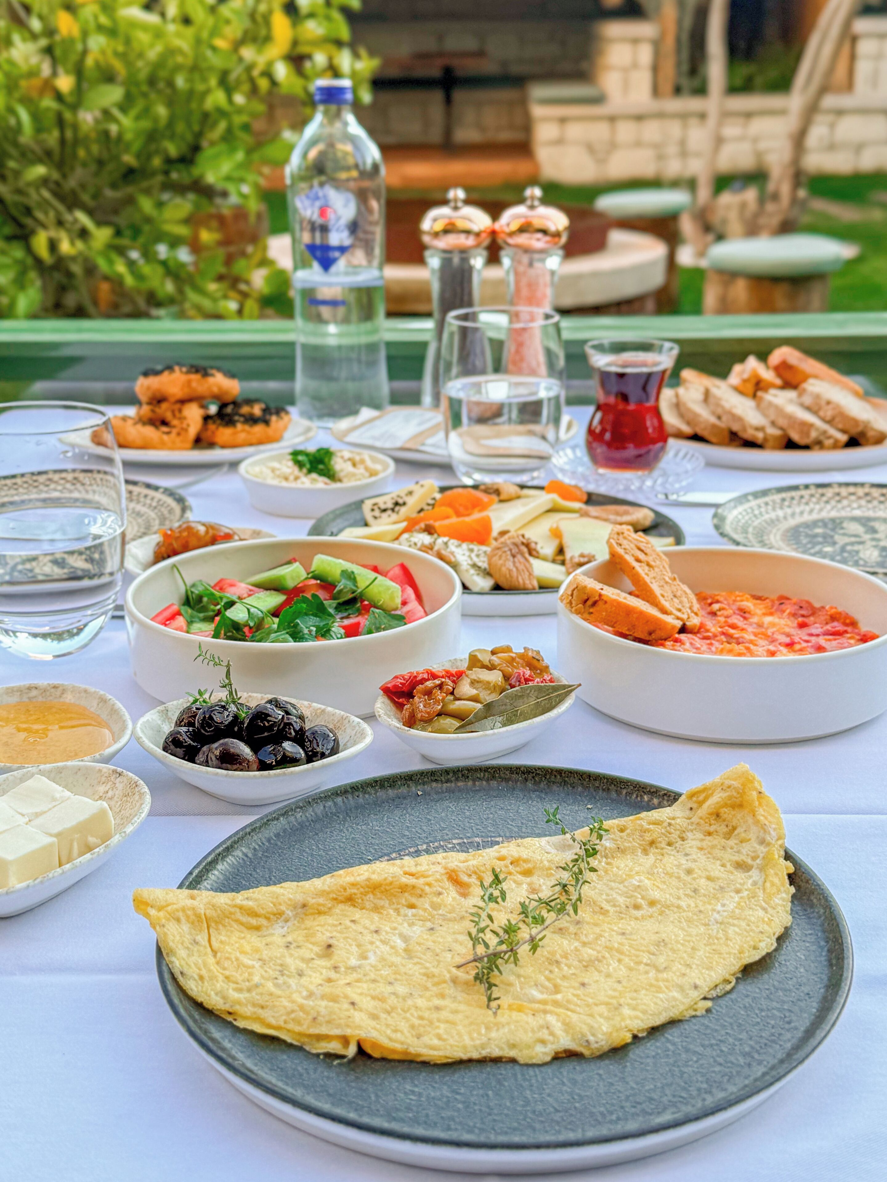 A table set with various dishes, including a large omelette, olives, cheese, and bread.