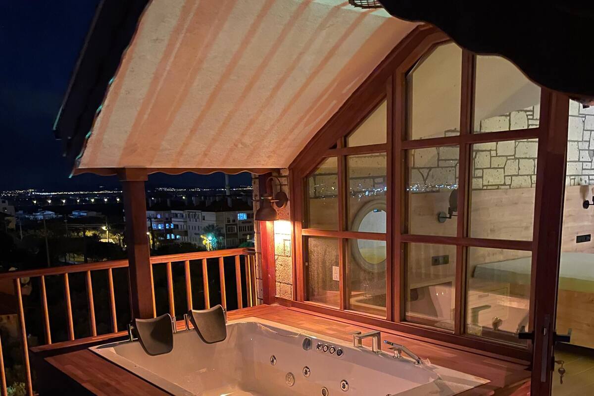A hot tub on a balcony with a view of the city at night.