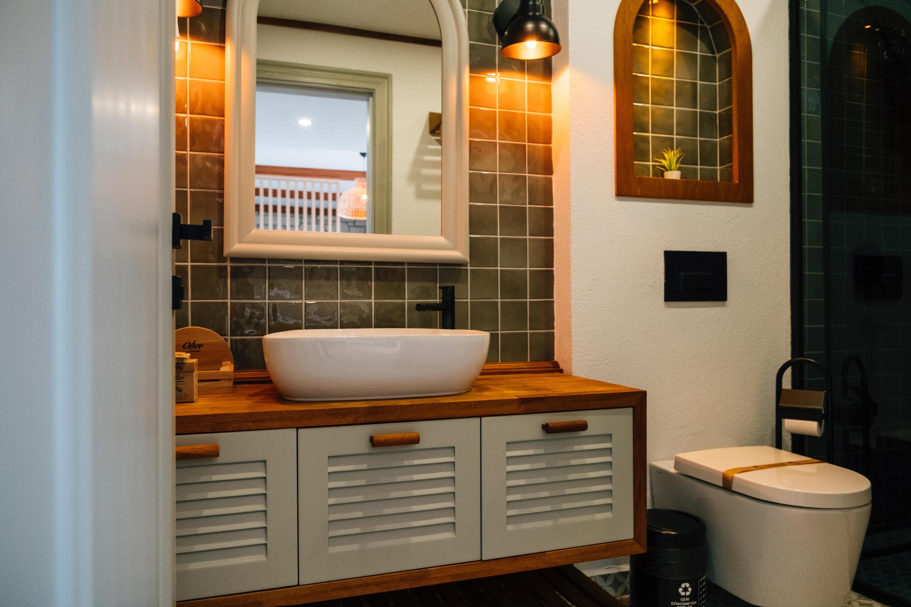 A bathroom with a white sink, wooden vanity, and a mirror.
