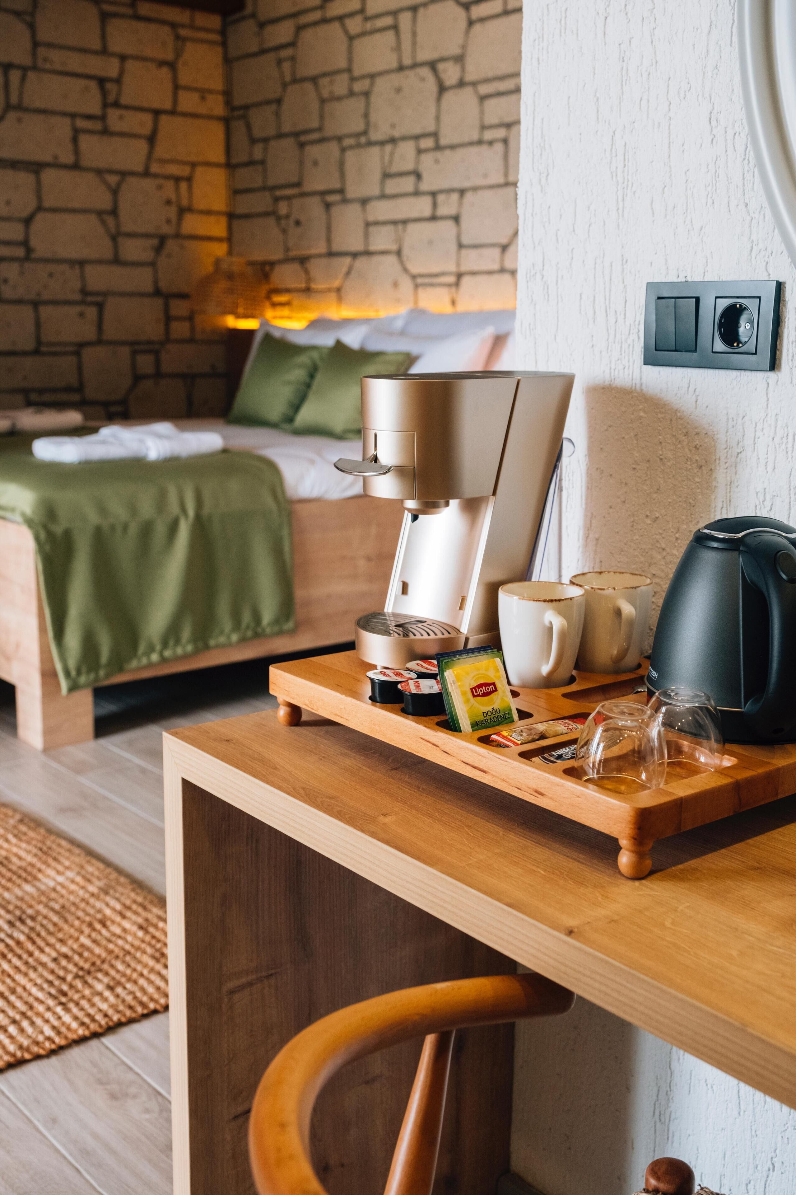 Una habitación de hotel acogedora con una cama de madera, una cafetera y una bandeja de desayuno sobre una mesa de madera.