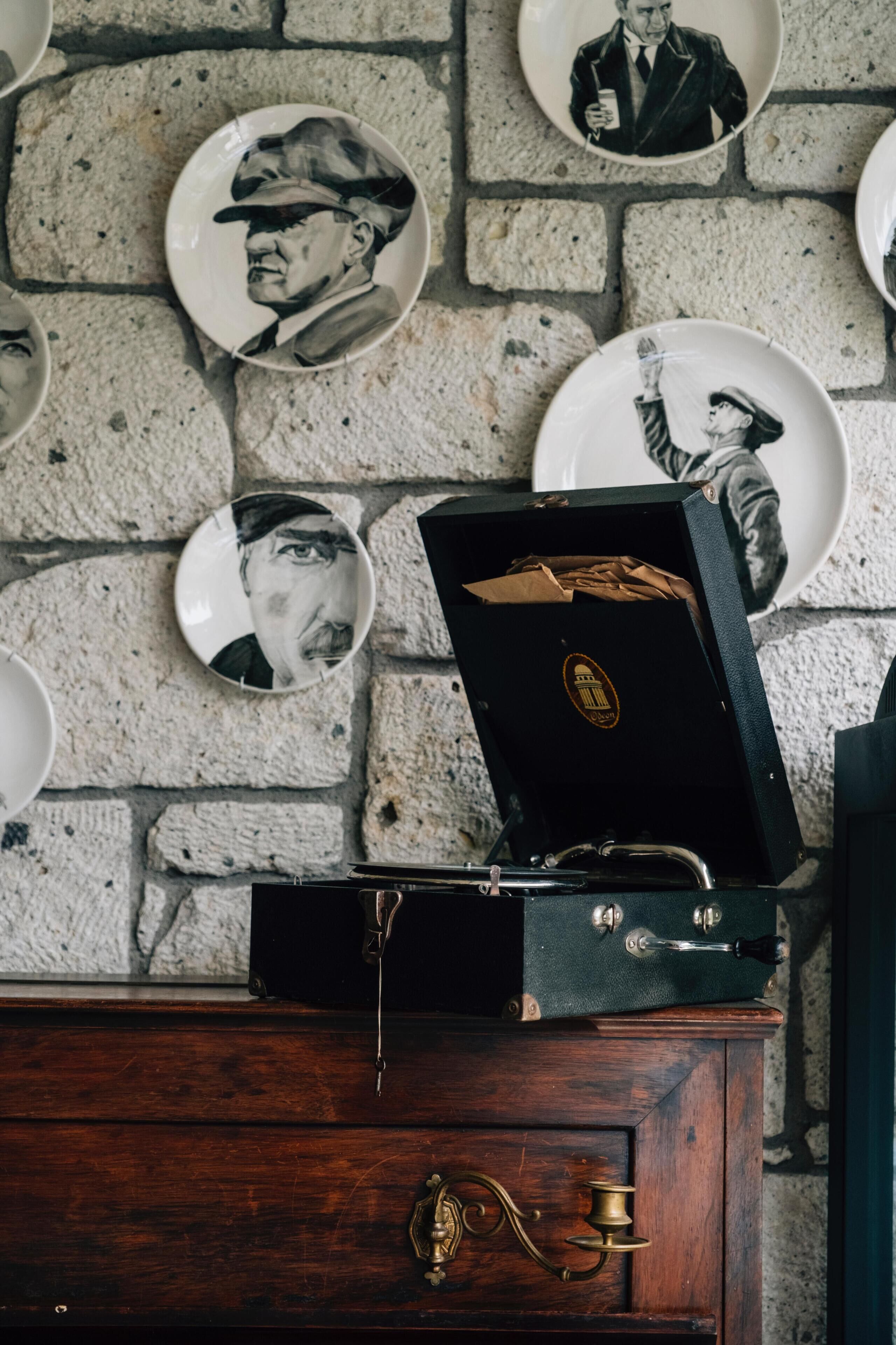 A wall with plates featuring portraits, a wooden cabinet with a brass lock, and a vintage radio.