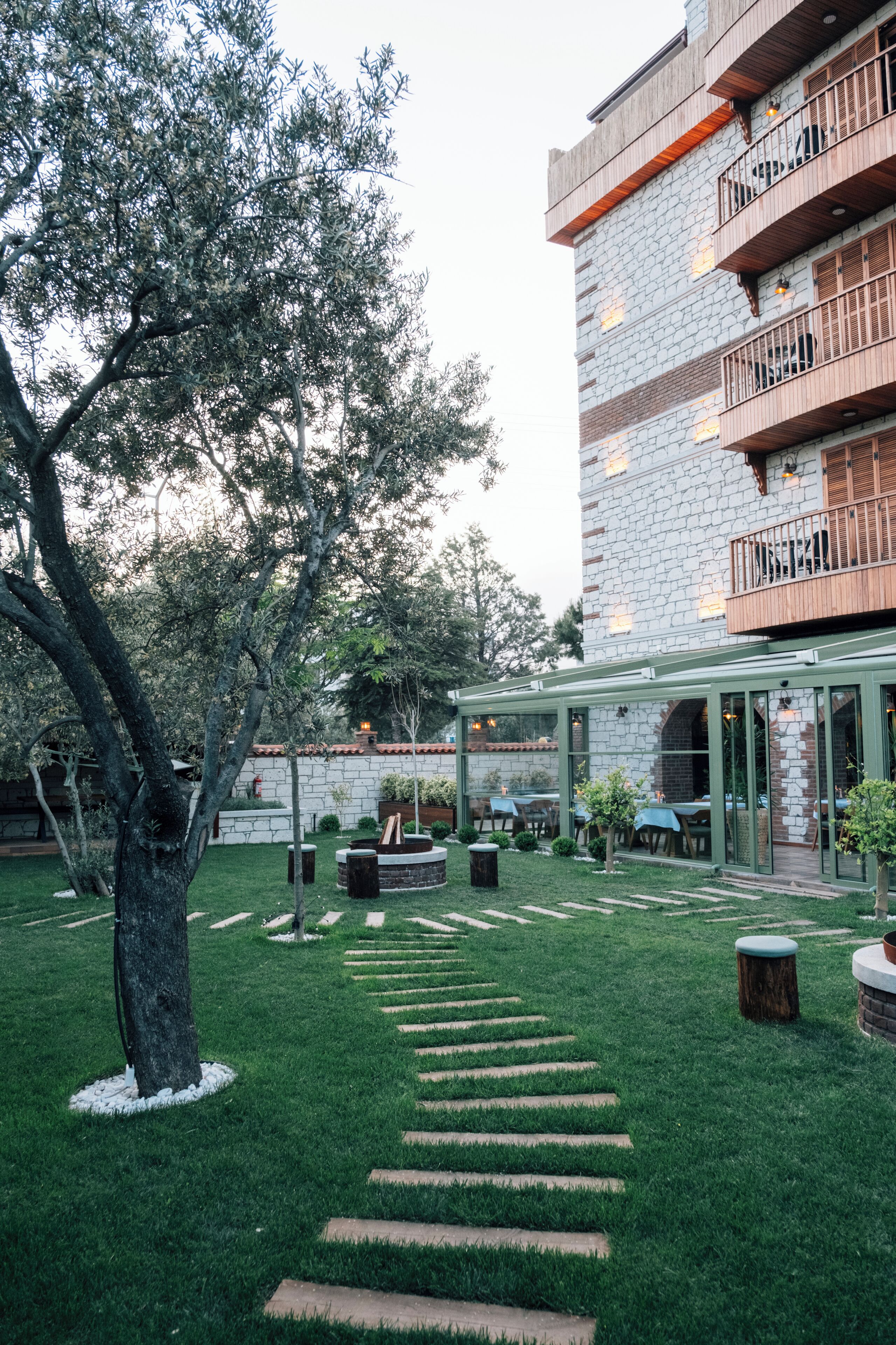 A courtyard with a stone building, outdoor seating, and a tree.