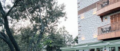 A courtyard with a stone building, outdoor seating, and a tree.