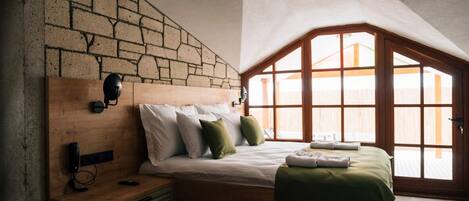 Un dormitorio con pared de piedra, cabecero de madera y un ventanal grande.