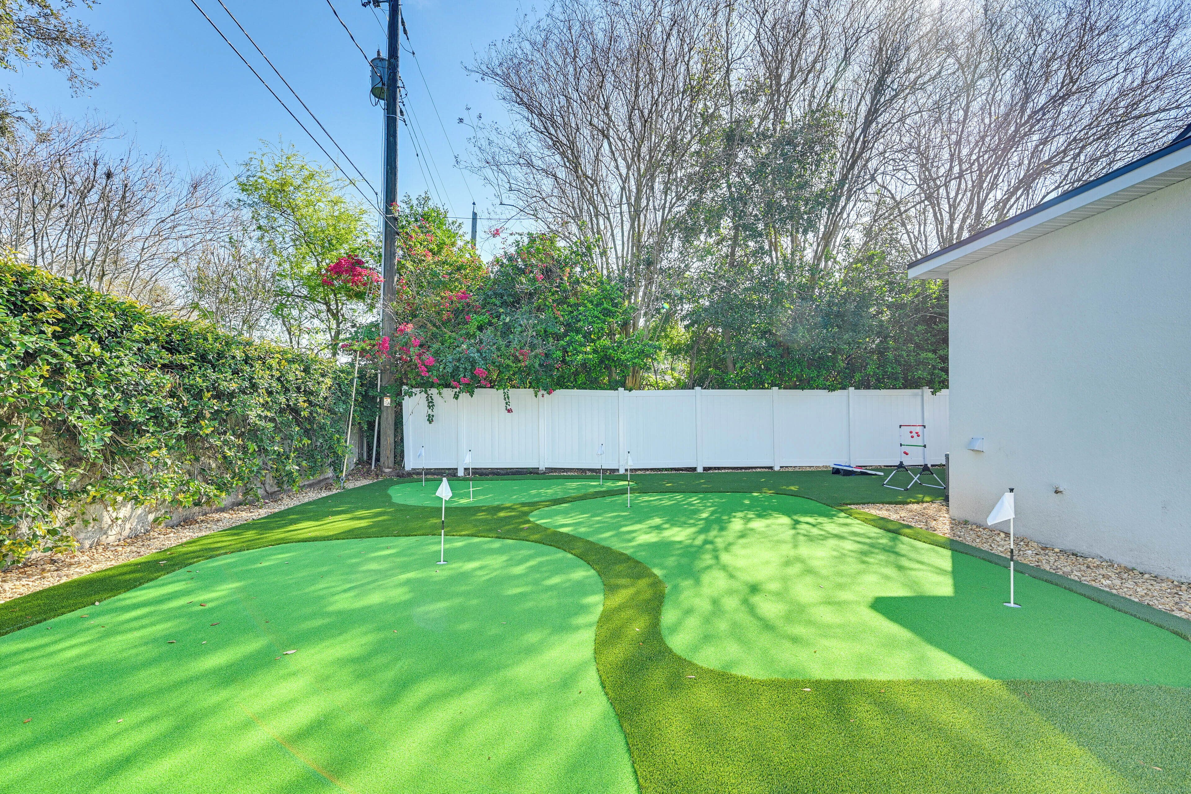 Un campo de golf con un club house blanco, rodeado de árboles y arbustos.