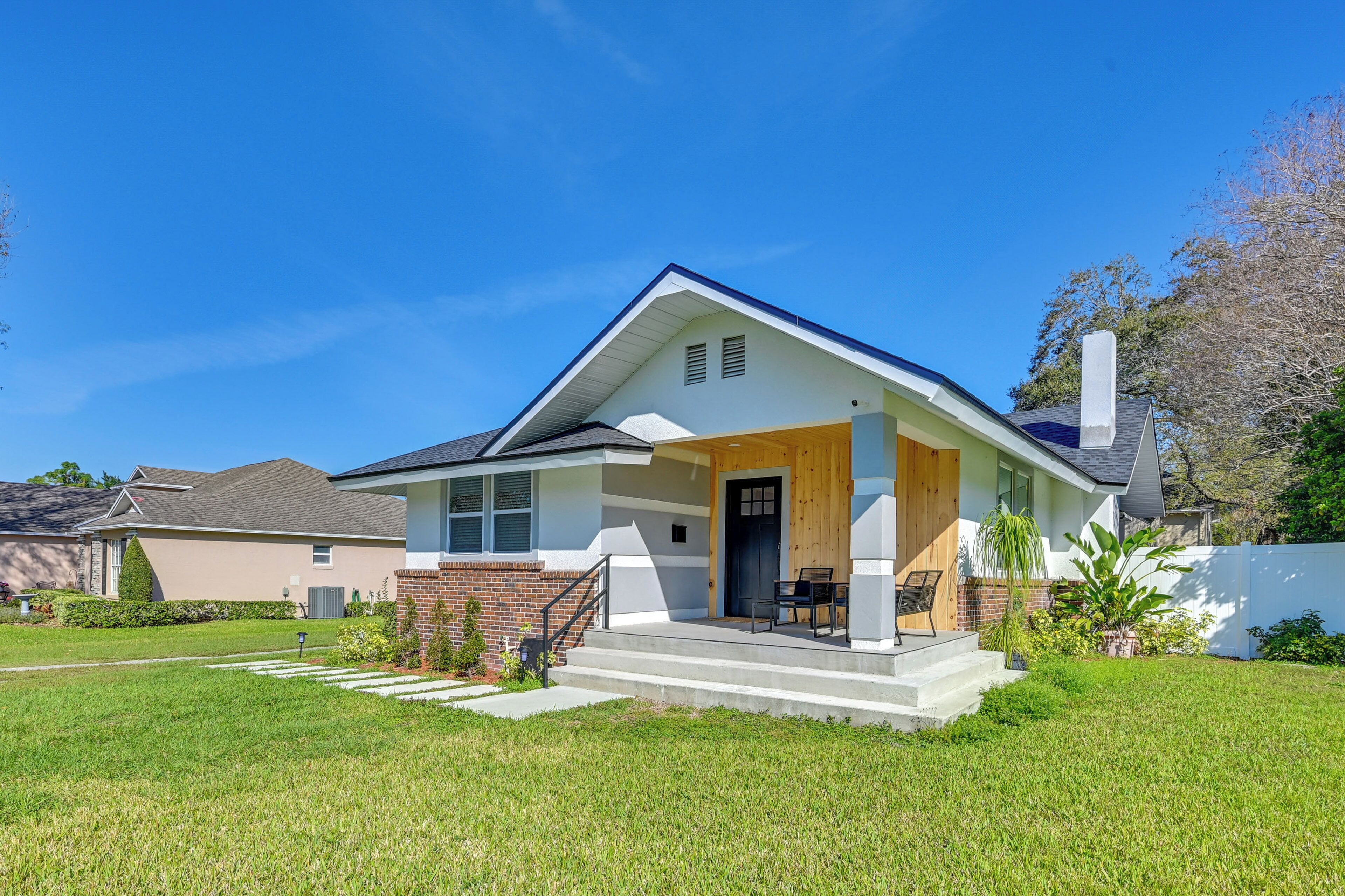 A modern two-story house with a front porch, a brick foundation, and a well-maintained lawn.
