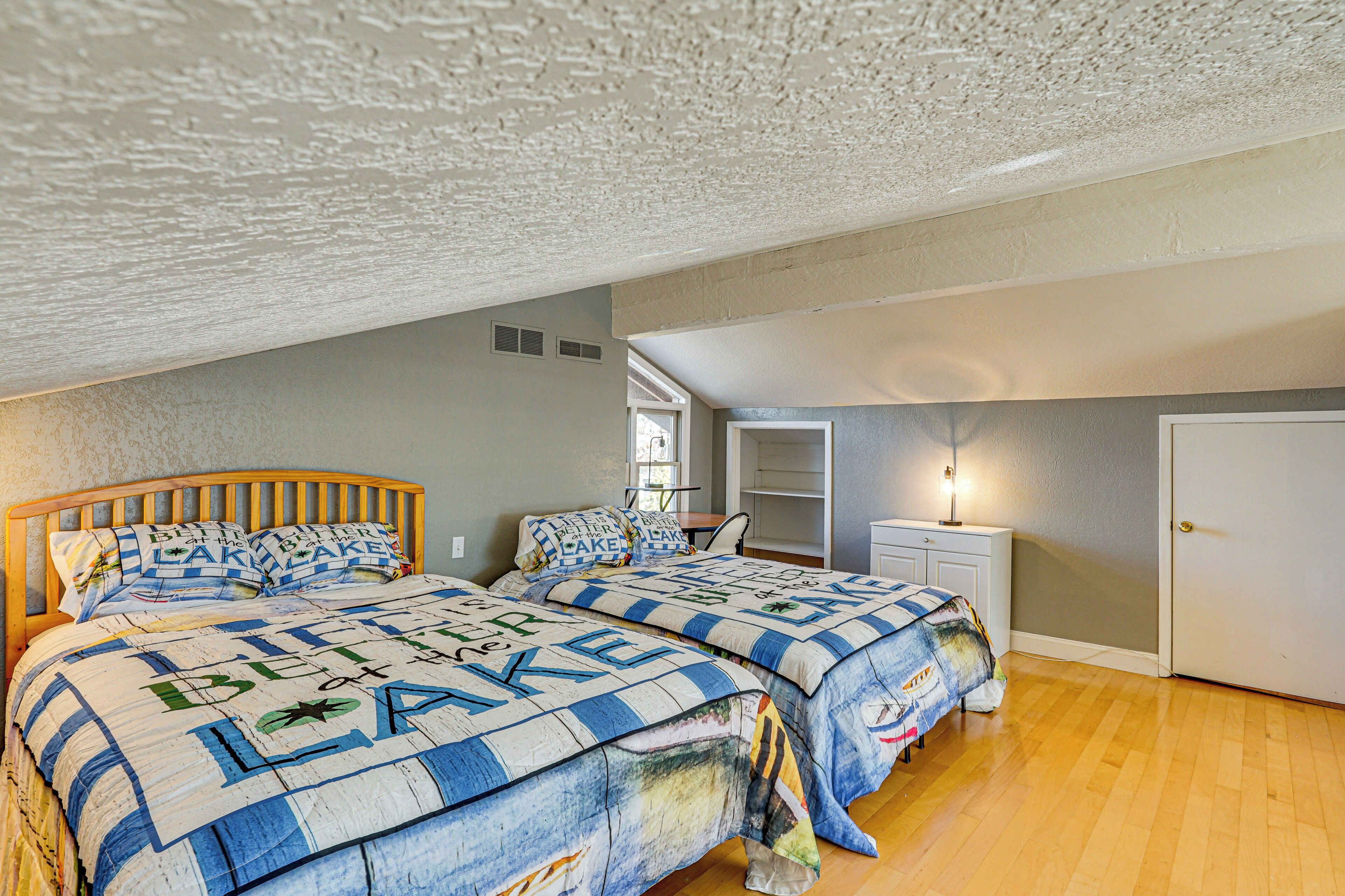 A bedroom with two beds, a desk, and a door.