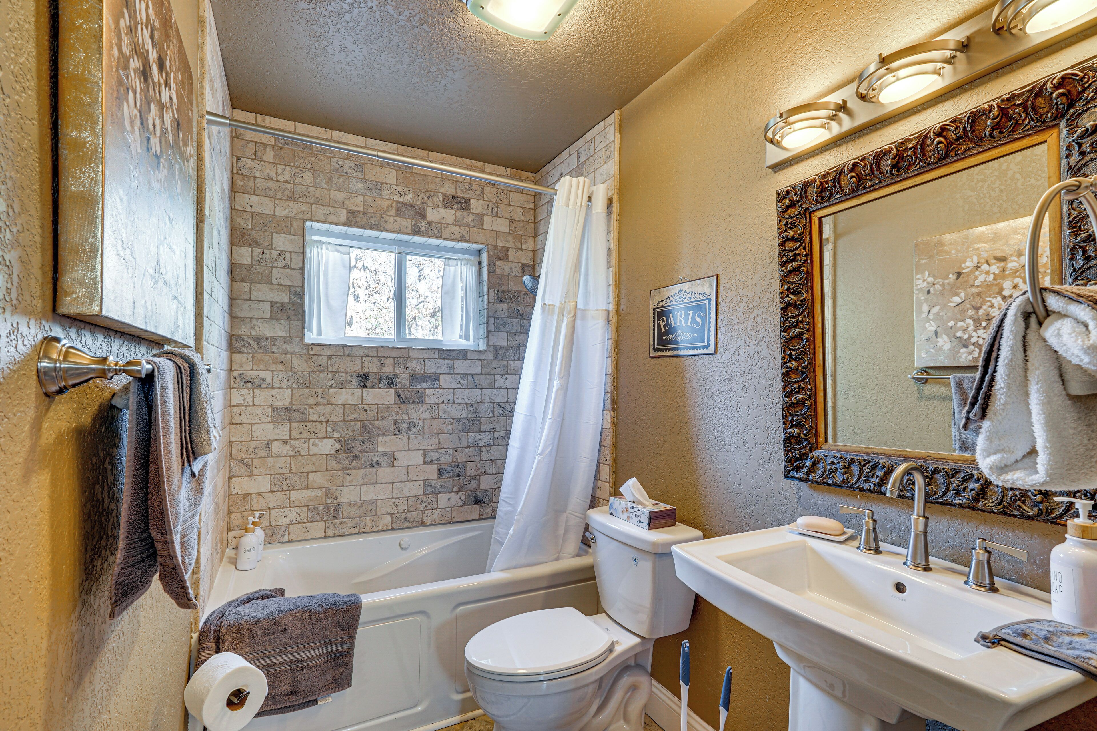 A bathroom with a bathtub, toilet, sink, and a large mirror.