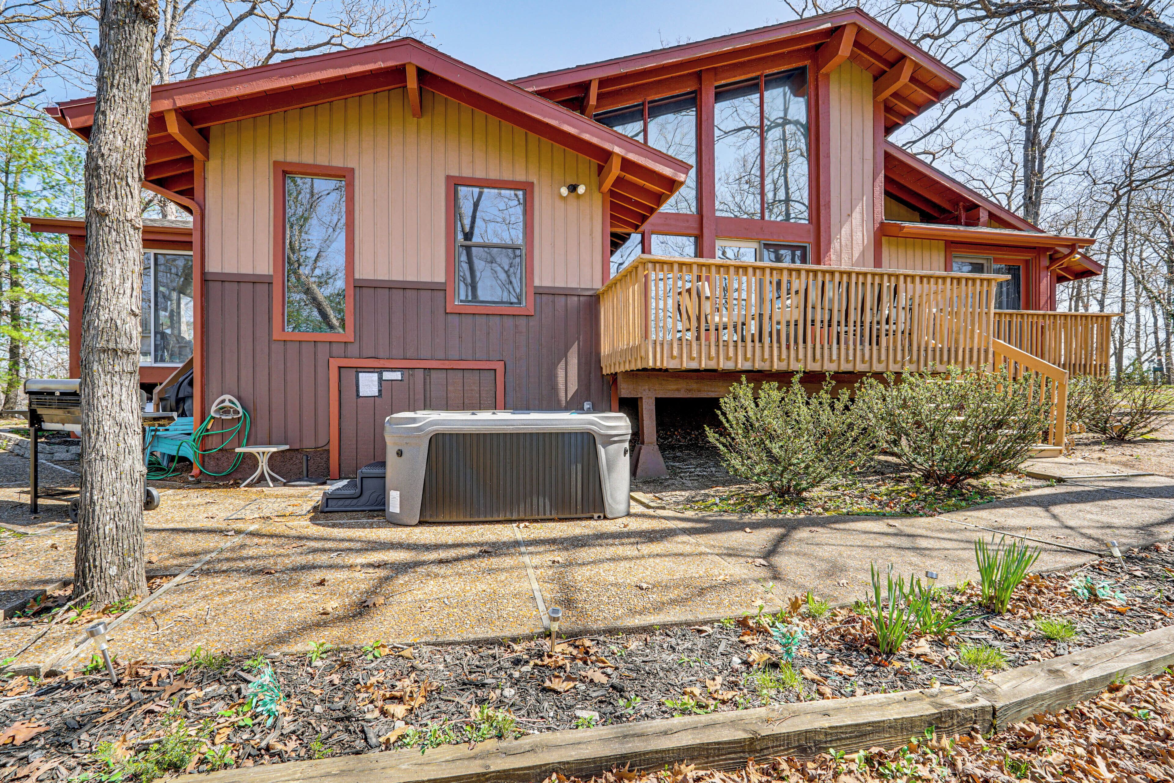 Ein zweistöckiges Haus mit einer Holzterrasse, einem Whirlpool und einem überdachten Außenbereich zum Sitzen.