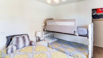 A bunk bed room with a ceiling fan, a bedside table with a lamp, and a wardrobe with a red and white design.