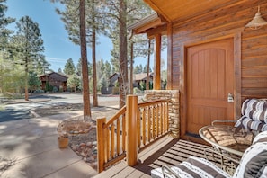 A wooden cabin with a porch, a stone wall, and a door. - Rustic Retreat w/ Spacious Deck in Show Low! (Show Low)