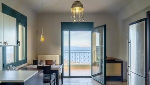Eine moderne Küche mit Essbereich, einer großen Schiebeglasdoor zum Balkon und Blick aufs Meer.