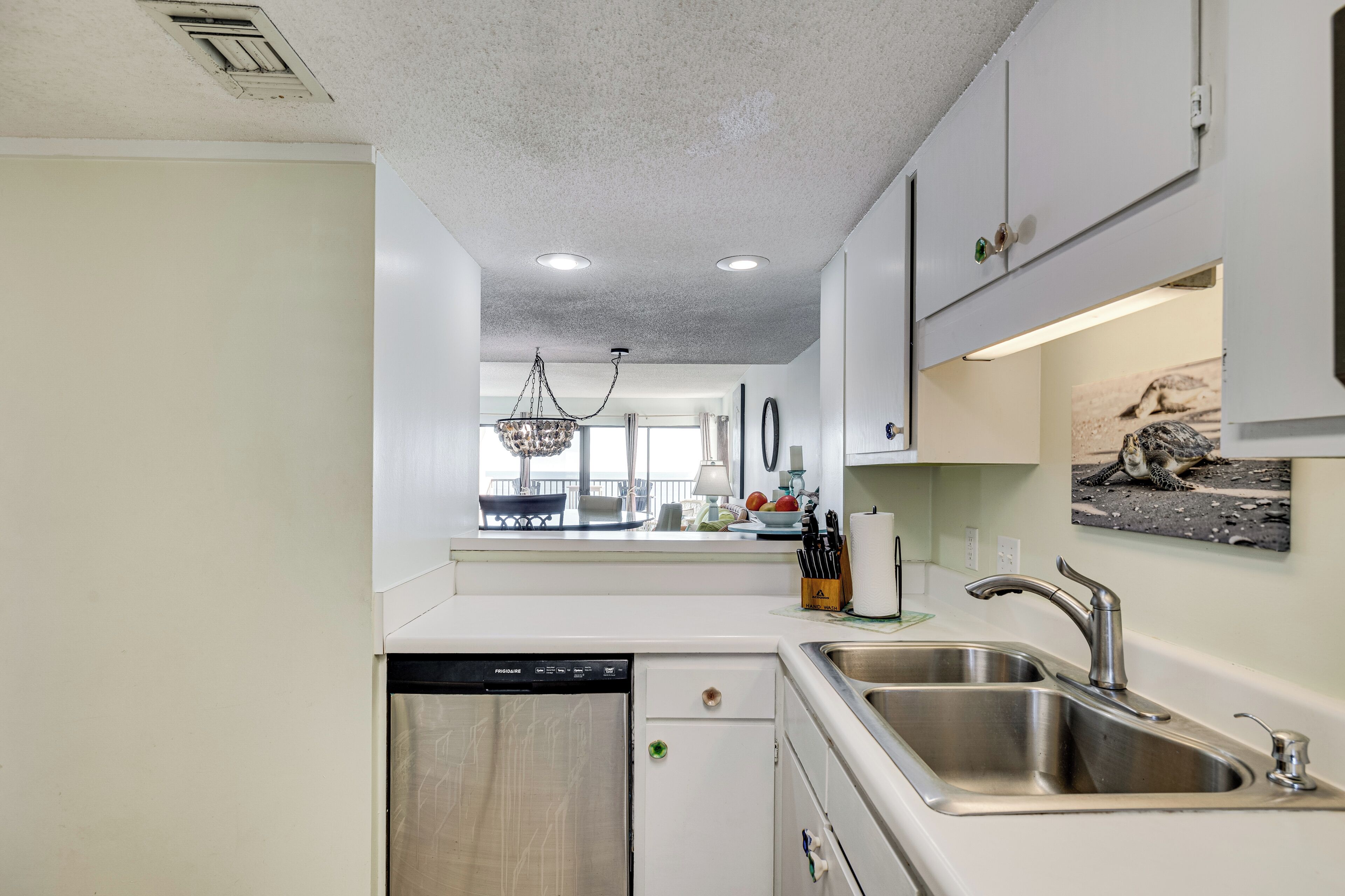 A modern kitchen with a dishwasher, double sink, and a view to the dining area.