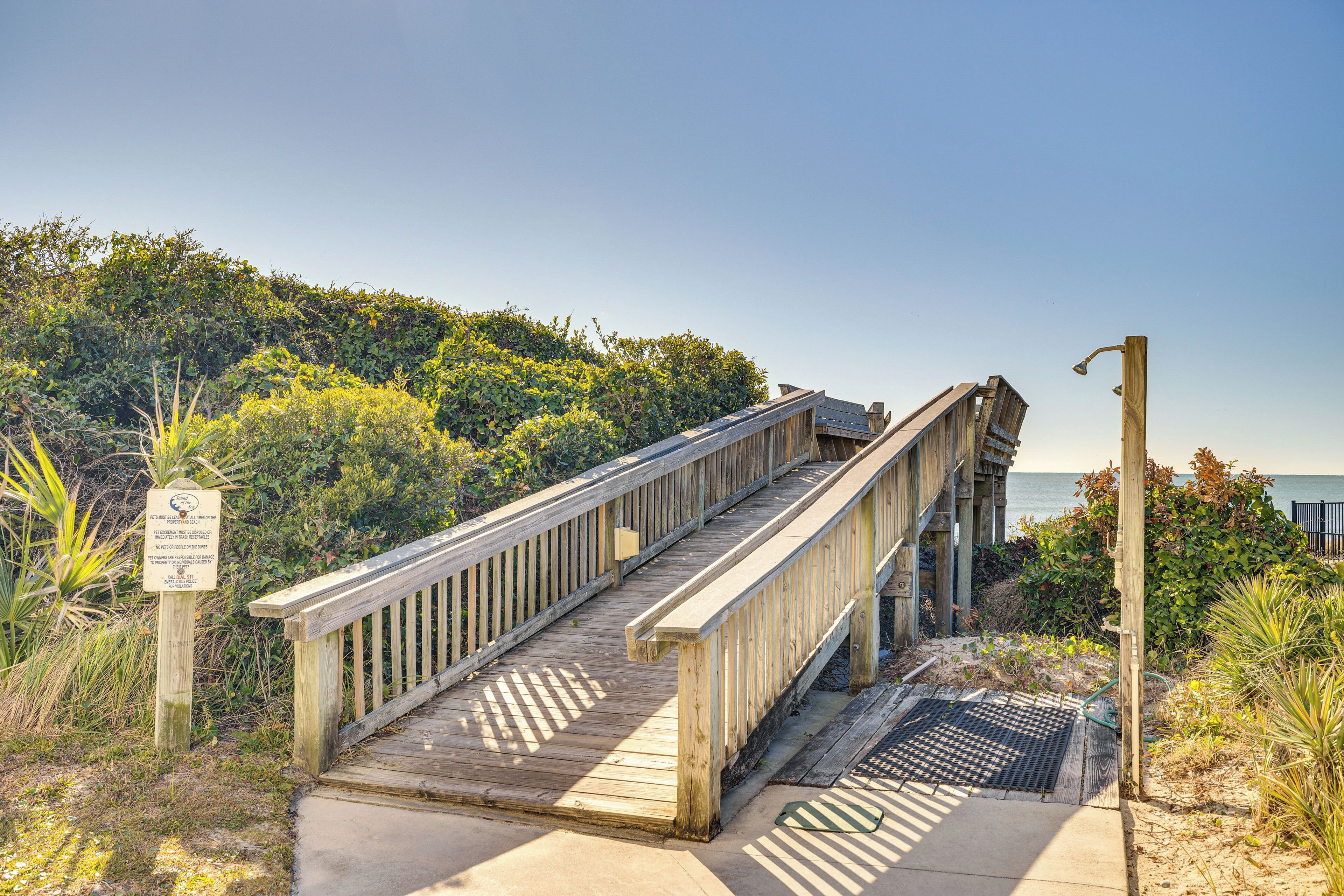 A wooden boardwalk leading to a beach with a sign indicating a nature trail.